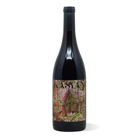 A dark wine bottle with a colorful label depicting a log cabin in a stand of birch trees and wildflowers.